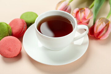 Tea, tulips and macaroons on beige background