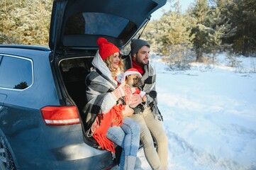 couple guy and girl sitting in car playing with dog in winter forest