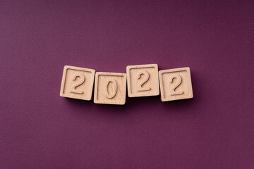 Color trends 2022, flat, lay, top view. The inscription is made of eco-friendly wooden cubes. The text is the color of the season on a burgundy background. Bright concept of trends 2022
