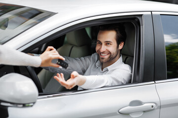 Fototapeta na wymiar Great purchase, dream come true. Smiling salesman handing over new car keys, dealership, rent and sales