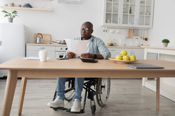 African american freelancer typing on computer, paperwork with documents on table