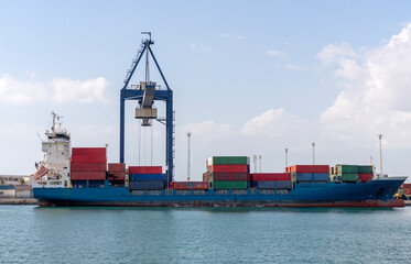 Container crane discharging container ship at container terminal.