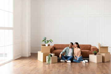 Arab family relaxing on floor in new home with boxes