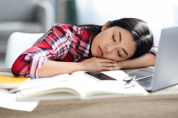 Exhausted Asian Female Student Sleeping At Desk With Books And Laptop