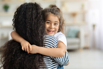 Cute little girl hugging her mother and cheerfully smiling
