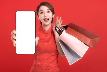 Happy chinese new year. Happy young Woman showing blank smart phone screen and shopping bags