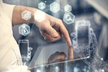 Double exposure of man's hands holding and using a digital device and tech theme hologram drawing. Technology concept.