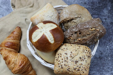 Varieties of bread with seeds, nuts and wholemeal in a basket on a dark background. Close-up