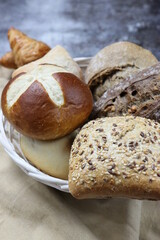 Varieties of bread with seeds, nuts and wholemeal in a basket on a dark background. Close-up