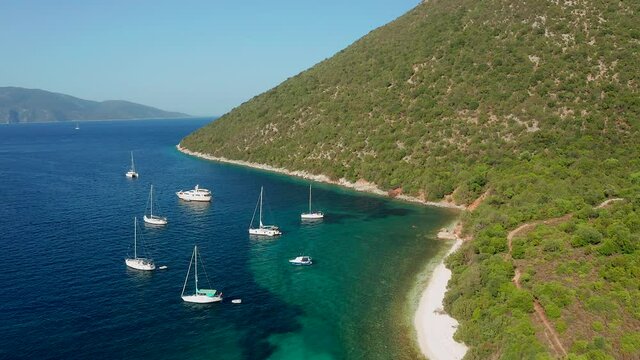 Aerial flyover touristic destination, yacht´s anchored on Pristine Turquoise Antisamos beach, Greece