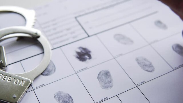 close up of a Man having his fingerprints taken at the police station, handcuffs ready