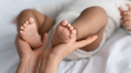 Closeup of woman holding feet of cute little African American baby