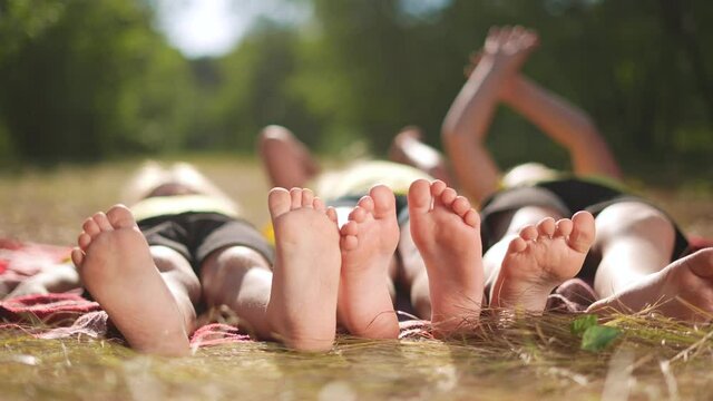 happy family. close-up of a kids leg feet lie on the grass in the summer park. children feet close-up team together happy childrens friendship. children sun lie in the park on the grass family