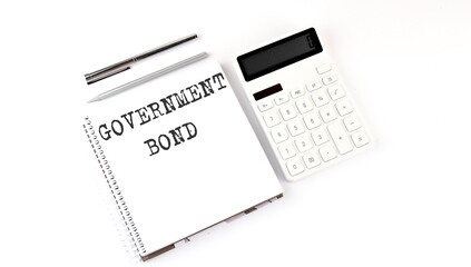 Notepad with text GOVERNMENT BOND with calculator and pen. White background. Business concept