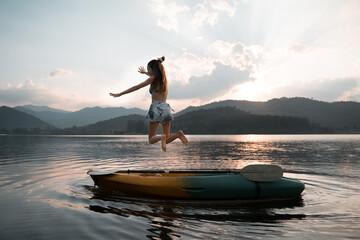 Kayaks in the lake. Tourists kayaking on mirror lake. travel activity. woman playing in water in sunset. active woman rowing boat in lake with mountain view in evening. jumping into water.