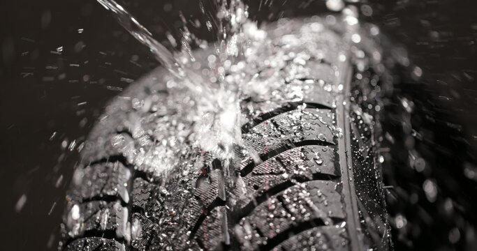 Water splashing on new car tyre closeup