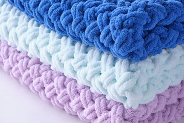 Warm, delicate and plush handmade baby blankets in three colors of blue, lilac and mint on background of window.