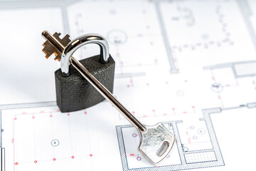 The lock and key to the new house on the design drawing of the apartment plan. Real estate sales and symbols