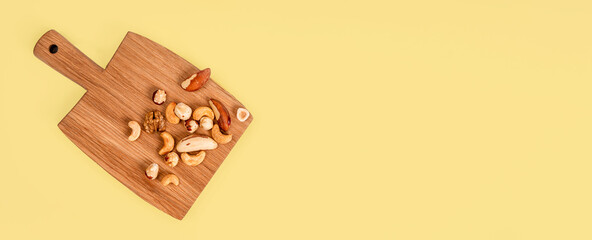 Wooden board with walnuts, hazelnuts and cashews on a white background. The concept of healthy eating and snacking