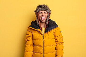 hispanic woman with cheerful and rebellious attitude, joking and sticking tongue out. winter concept