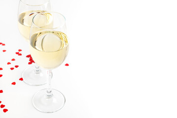 Two glasses of white wine and decor of hearts. Wine glasses over a white backdrop with copy space