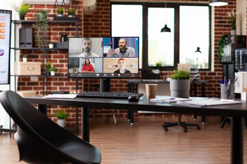 Computer with video call conference on desk in empty office. Online business meeting with video conference on monitor for remote communication with coworkers. Teleconference call