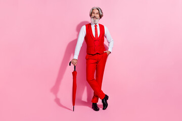 Full length body size view of attractive cheery minded grey-haired man with parasol thinking isolated over pink pastel color background © deagreez