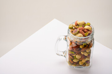 Glass jar filled with a variety of nutrition and healthy snacks and nuts on a white background