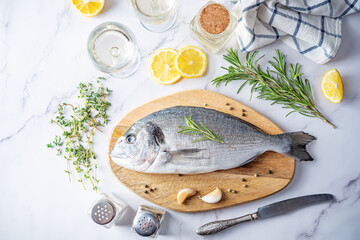 Raw fresh dorada fish with lemon slices and greens