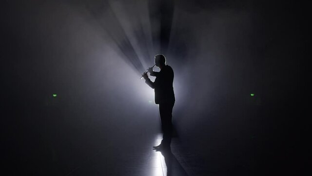 Person is playing the duduk, flute on black background 4K. Man playing classical music in the dark on a stage