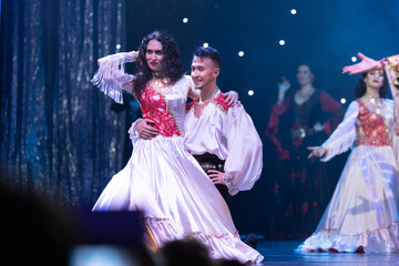A collective of musicians, singers and dancers in gypsy costumes perform on stage.