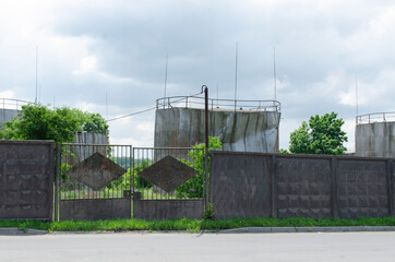 Fototapeta na wymiar Oil storage tanks behind the concrete fence 