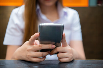 Hand of woman using smartphone on wooden table