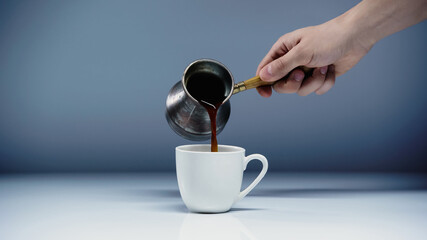 cropped view of man pouring coffee into cup on white and grey.