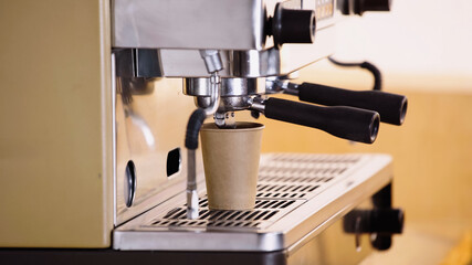 professional coffee maker pouring drink in paper cup in modern coffee shop.