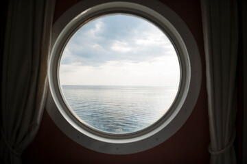 Blick aus einem runden Schiffsfenster auf das Meer