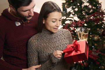 Woman holding Christmas present and standing next to her boyfriend