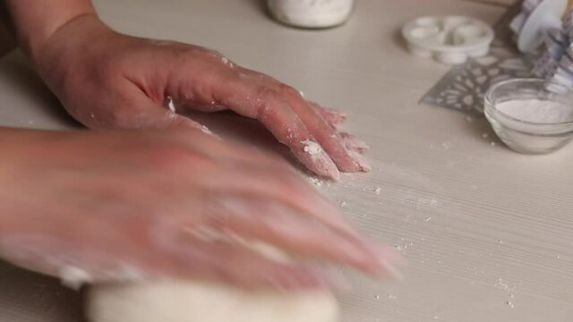 A woman makes confectionery mastic from powdered sugar. Kneads it with his hands. Close-up..