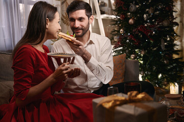 Woman tasting cake while celebrating Christmas with her boyfriend