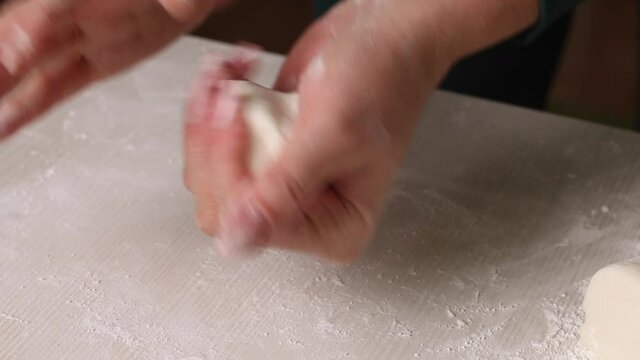 A woman makes confectionery mastic from powdered sugar. Kneads a lump of mastic in his hands. Close-up.