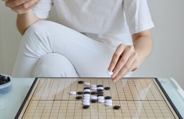 Straight view of GO board game table with woman hand holding a stone