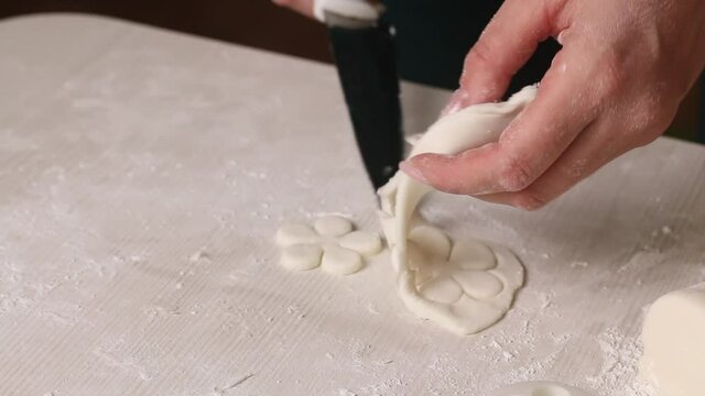 A woman makes confectionery mastic from powdered sugar. I rolled out the mastic and cut out figures from it. Close-up..