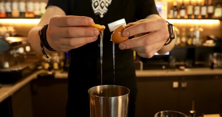 The barman prepares a delicious cocktail at the bar. The bartender adds raw eggs to the drink.