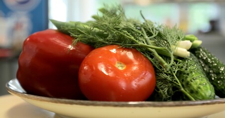 Video of freshly washed vegetables and greens: tomatoes, sweet pepper, green onions and dill spinning on a round white plate. Rotating vegetables.