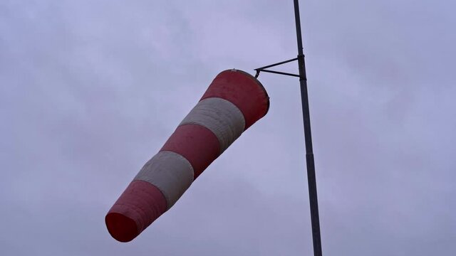 Wind sock at Z&uuml;rich Airport on a windy and rainy winter day. Slow motion movie shot December 28th, 2021, Zurich, Switzerland.