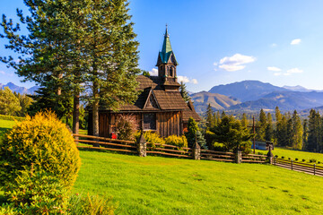 Beautiful wooden church Plazowka built in traditional style architecture on green meadow with view of Tatra Mountains, Koscielisko, Poland - 477308597