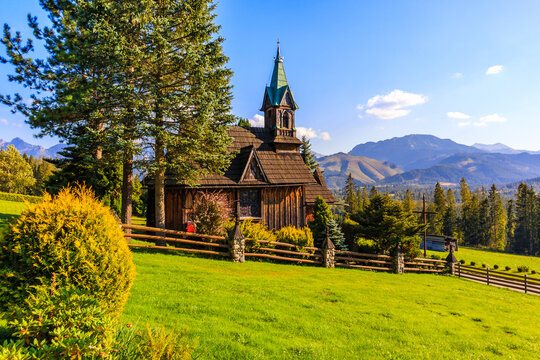 Beautiful wooden church Plazowka built in traditional style architecture on green meadow with view of Tatra Mountains, Koscielisko, Poland
