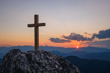Silhouettes of crucifix symbol on top mountain with bright sunbeam on the colorful sky background