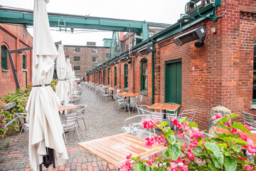 Outodoor tables along a brick alley lined with renovated warehouses in a historic district on cloudy autumn day