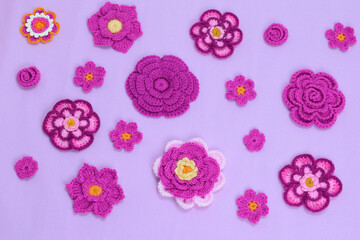 Crocheted flowers in different sizes on a white background - obrazy, fototapety, plakaty